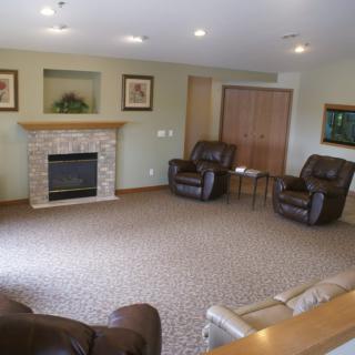 A cozy living room featuring a fireplace, comfortable armchairs, and a carpeted floor.