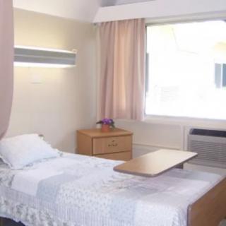 A clean and bright hospital room with a single bed and bedside table.