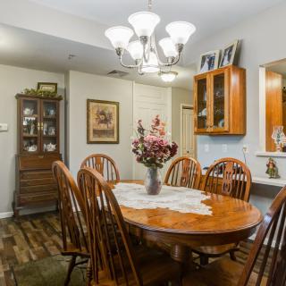 A cozy dining room with a wooden table and chairs, adorned with a decorative centerpiece under a chandelier.