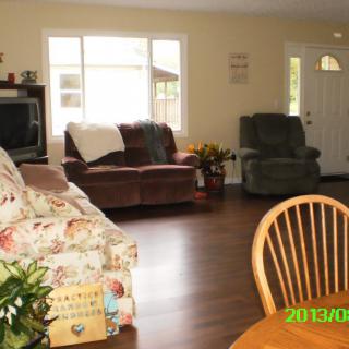 A cozy living room with a floral sofa, armchairs, and a window letting in natural light.