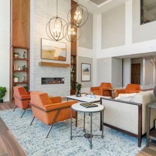 A modern living room with orange chairs and elegant chandeliers.