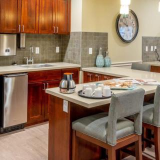 A modern kitchen with wooden cabinets, an island counter, and bar stools.