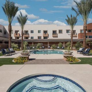 A serene outdoor pool area at a resort, surrounded by palm trees and lounge chairs under a clear blue sky.