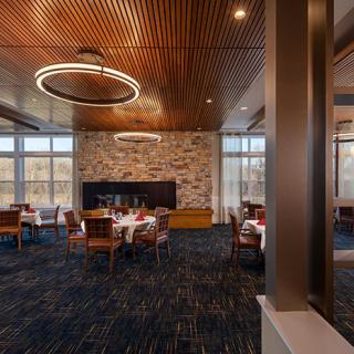 A modern dining area featuring a wooden ceiling, stone accent wall, and elegant lighting fixtures.