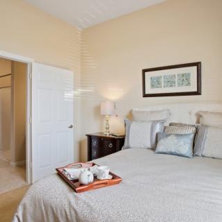 A cozy bedroom with a neatly made bed, featuring a tray and tea set.