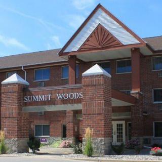 The front entrance of the Summit Woods residential building, featuring a brick facade and peaked roof design.