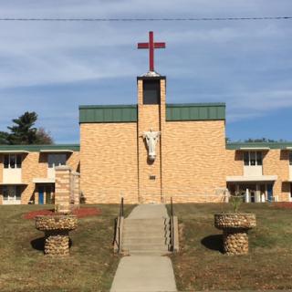 A church building featuring a prominent cross on top, surrounded by landscaped grass.