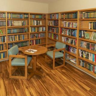 A cozy library corner with bookshelves, a round table, and chairs.