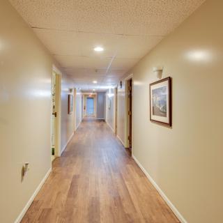 A well-lit hallway with wooden flooring and artwork adorning the walls.