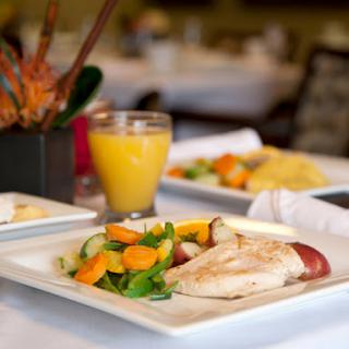 A delicious breakfast featuring grilled chicken, fresh salad, and a glass of orange juice.