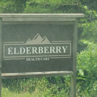 Sign for Elderberry Health Care surrounded by greenery.