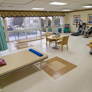 A well-equipped physical therapy and rehabilitation room with exercise machines and a treatment table.