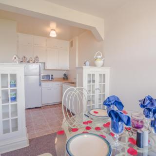 A cozy dining area with a view into the kitchen, featuring a beautifully set table with blue napkins.