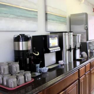 A self-serve coffee and beverage station with various machines and cups arranged on a counter.