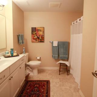 A well-decorated bathroom with a sink, toilet, shower curtain, and colorful towels.