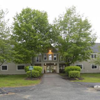 A symmetrical building with an entrance flanked by trees and a pathway leading up to it.