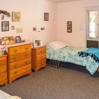 A cozy bedroom with a single bed, dressers, and wall decorations.