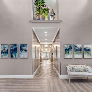 A modern hallway with elegant artwork and plants, featuring wood flooring and contemporary lighting.