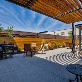 A modern outdoor patio with seating and a pergola under a clear blue sky.