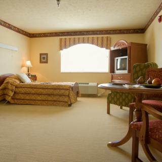 A cozy hotel room with a comfortable bed and traditional furnishings, featuring a television and soft lighting.
