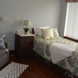 A cozy bedroom with a single bed, decorative pillows, and a bedside lamp.
