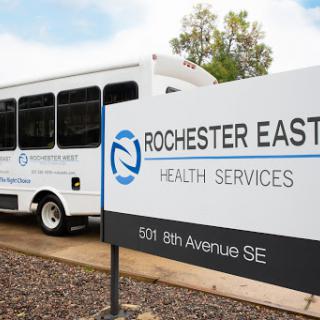 The Rochester East Health Services sign next to a parked service bus.