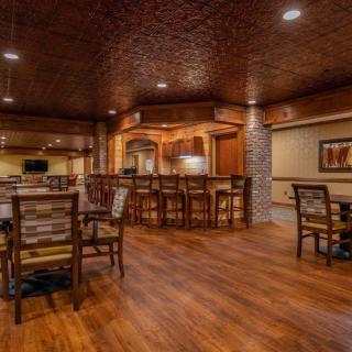 A cozy restaurant interior with a bar and seating area, featuring warm lighting and wooden floors.