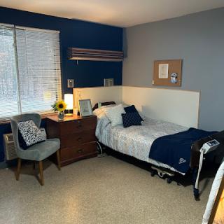 A cozy and organized bedroom featuring a single bed, desk, and comfortable seating.