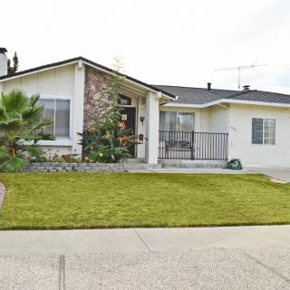 A single-story suburban house with a well-maintained lawn and a driveway.