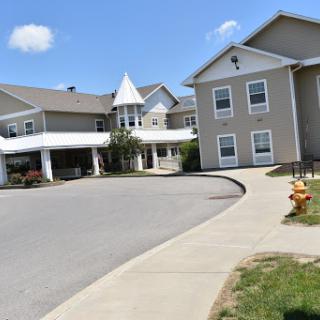 A view of a multi-story residential building with a curved driveway under a clear blue sky.
