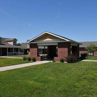 A suburban residential building with a brick exterior and well-maintained lawn under a clear blue sky.