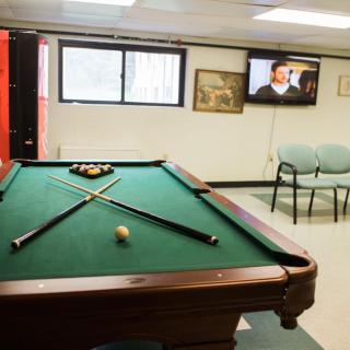 A recreation room featuring a pool table and a television on the wall.