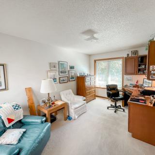 A cozy living room with a home office setup, featuring comfortable seating and decorative elements.