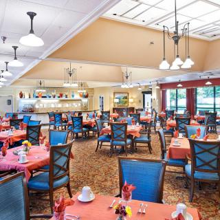 A bright dining room with elegantly set tables and decorative chandeliers.