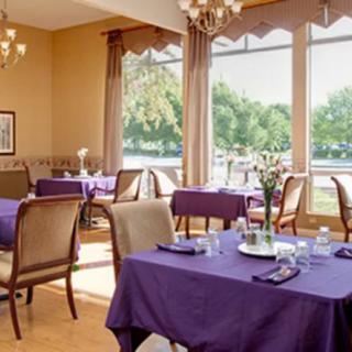 A cozy restaurant dining area with purple tablecloths and large windows offering a scenic view.