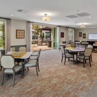 A spacious and well-lit dining area with tables and chairs, featuring large windows that provide an open view to the outside.