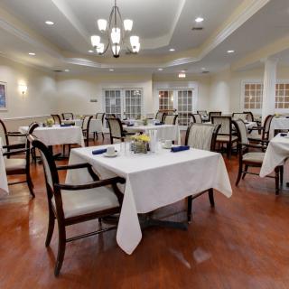 An elegant dining area with neatly arranged tables and chairs, featuring chandeliers for ambient lighting.