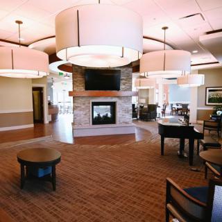 A spacious and well-lit lobby with a central fireplace, surrounded by comfortable seating and modern lighting.