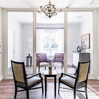 A modern living space featuring two chairs around a small table, with additional seating visible in the background.