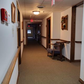 A well-lit hallway with a chair and framed pictures on the walls.