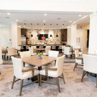 A modern dining area with neatly arranged tables and chairs, featuring stylish lighting and contemporary decor.