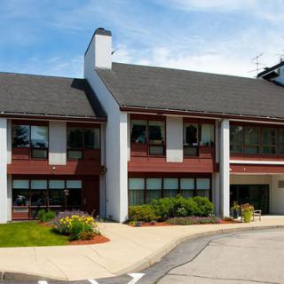 A modern commercial building with large windows and landscaped surroundings under a clear blue sky.