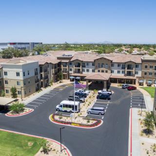 Aerial view of a modern building with a parking lot and landscaped surroundings.