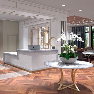 A modern lobby with elegant wood flooring and a beautifully arranged reception area, featuring an orchid centerpiece on a round table.