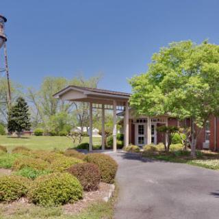 A building entrance with a driveway, surrounded by trees and bushes, next to a water tower.
