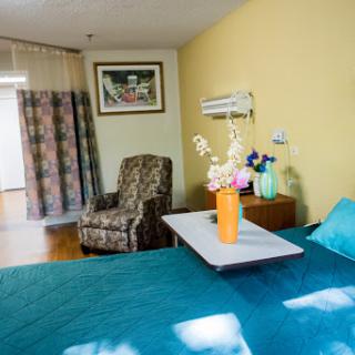 A cozy and well-decorated bedroom with a vibrant blue bedspread, a comfortable chair, and a vase of fresh flowers.
