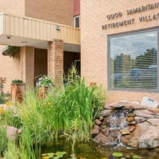 A view of the entrance to a retirement village, featuring a well-maintained garden and water feature.