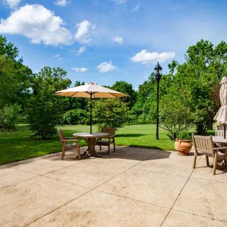 A peaceful backyard patio with outdoor furniture and an umbrella, surrounded by lush greenery.