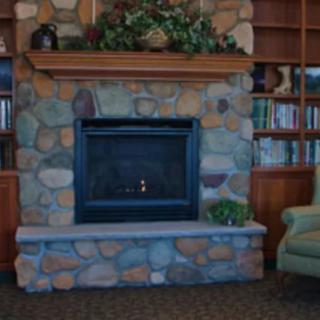 A cozy stone fireplace surrounded by bookshelves in a comfortable room.