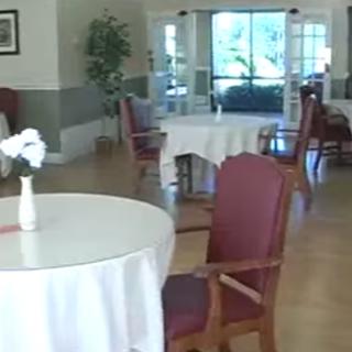 A spacious dining area featuring empty tables and elegant furnishings, with natural light streaming in.